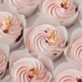 Set of cupcakes with pink whipped cream top decorated with edible golden petals and red dried berries. Close-up shot of cupcakes in the white background. Macro shot